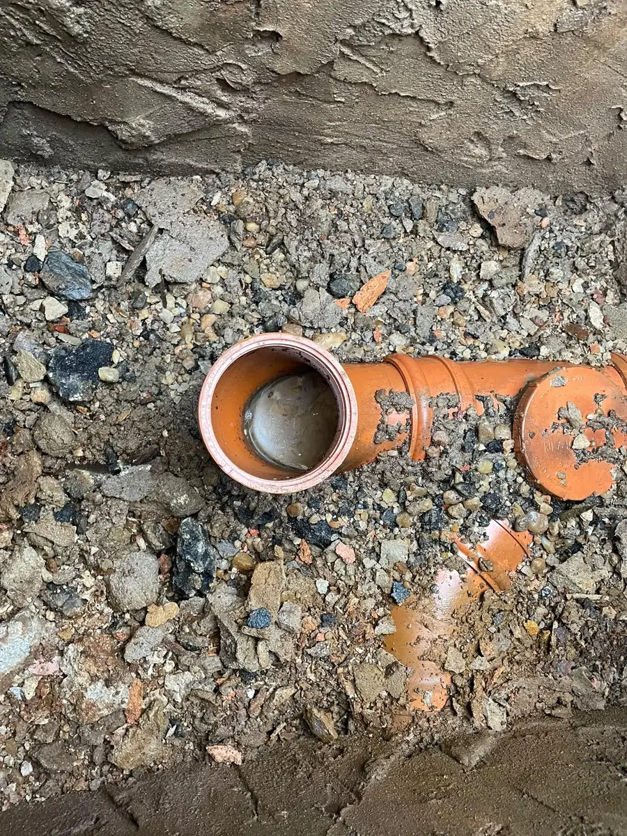 New orange plastic drainage pipe and bend laid in stone